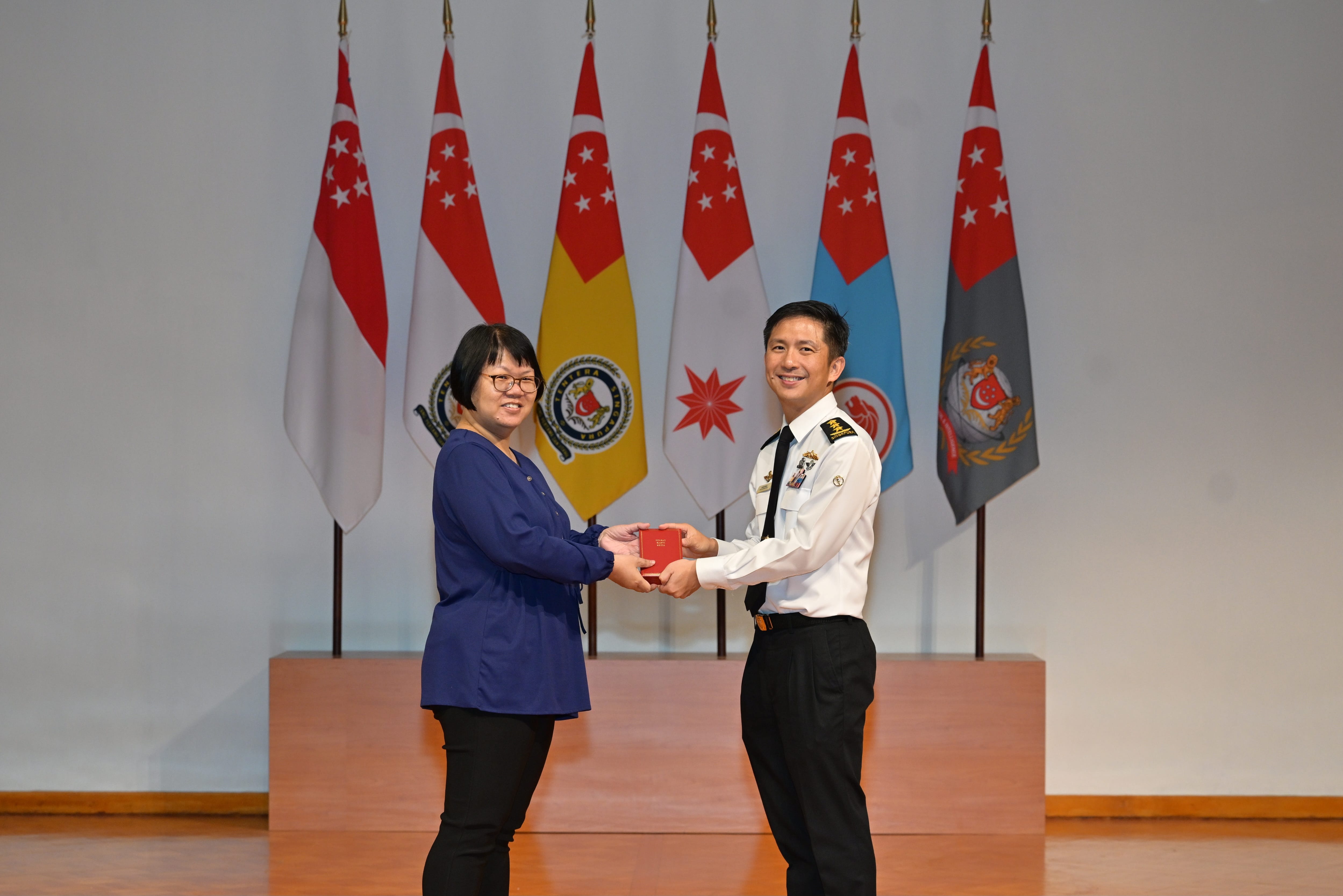Chief of Defence Force Vice Admiral Aaron Beng (right) presenting the Long Service Medal to Ms Lim Siew Peng (left).